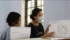 Two girls are holding their drawings.